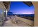 Enjoy the skyline from this balcony with chairs, a table, and wrought iron railing at twilight at 12125 Edgehurst Ct, Las Vegas, NV 89138