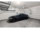 Spacious garage featuring a sleek black sports car, overhead storage racks, and an automatic garage door at 12125 Edgehurst Ct, Las Vegas, NV 89138