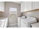 Bright laundry room with white cabinets, countertops, a window, and a modern washer and dryer set at 12125 Edgehurst Ct, Las Vegas, NV 89138