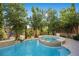Backyard pool with a built-in spa, surrounded by lush greenery and a stone tile border, ideal for relaxation and entertainment at 12125 Edgehurst Ct, Las Vegas, NV 89138