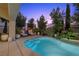 Inviting backyard pool with lounge chairs and lush landscaping at dusk at 12125 Edgehurst Ct, Las Vegas, NV 89138