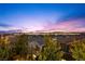 City lights under a colorful sunset sky, seen from among the trees and rooftops at 12125 Edgehurst Ct, Las Vegas, NV 89138