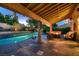 Backyard covered patio featuring a fire pit, lounge seating, and a sparkling pool creating an inviting outdoor space at 13 Cozy Glen Cir, Henderson, NV 89074