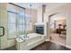 Luxurious bathroom featuring a soaking tub, a glass enclosed shower, and a view into the main bedroom at 13 Cozy Glen Cir, Henderson, NV 89074