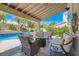 Inviting covered patio with a fire pit, comfortable lounge seating, and views of the sparkling backyard pool at 13 Cozy Glen Cir, Henderson, NV 89074