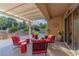 Covered patio with comfortable red cushioned seating around a stone fire pit, with a view of the backyard at 17 Chatmoss Rd, Henderson, NV 89052