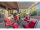 Covered patio with comfortable red cushioned seating around a stone fire pit at 17 Chatmoss Rd, Henderson, NV 89052