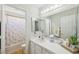 Bright bathroom with white-tiled counters, vanity lights, decorative mirrors, and a shower/tub combination at 1707 Navarre Ln, Henderson, NV 89014