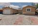 A tan single story home features desert landscaping and an attached garage at 1911 Venalynne St, Las Vegas, NV 89156