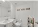 Bright, minimalist bathroom with a pedestal sink, toilet, and modern wall decor at 2885 Timber Country Rd, North Las Vegas, NV 89086