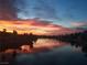 Scenic waterfront view with a vibrant sunset reflecting on the calm water and silhouetting the surrounding palm trees at 3125 N Buffalo Dr # 1080, Las Vegas, NV 89128