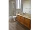 Bright bathroom with wood vanity, dual sinks, and a shower/tub combo with sliding glass doors at 4931 Crystal Breeze Ln, North Las Vegas, NV 89031