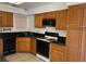 Well-lit kitchen featuring black appliances, wooden cabinets, and tiled flooring, perfect for cooking at 4931 Crystal Breeze Ln, North Las Vegas, NV 89031