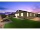 Backyard view featuring a yard with green grass and a stone patio at sunset at 5918 Peridot Falls Ave, Las Vegas, NV 89130
