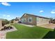 A well-manicured backyard with green grass, covered patio, and stone features at 5918 Peridot Falls Ave, Las Vegas, NV 89130