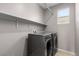 Clean laundry room with a window, shelving and modern, gray front-loading washer and dryer at 5918 Peridot Falls Ave, Las Vegas, NV 89130