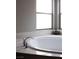 A bathroom featuring a stand alone tub with marble surround beneath large windows for natural light at 5976 Rockway Glen Ave, Las Vegas, NV 89141