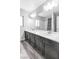 A bathroom featuring double sinks, white quartz counters, grey floors, and a shower behind the mirror at 5976 Rockway Glen Ave, Las Vegas, NV 89141