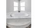 A bathroom featuring a stand alone tub with marble surround beneath large windows for natural light at 5976 Rockway Glen Ave, Las Vegas, NV 89141