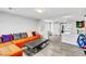 An open living room with an orange couch, ottoman, and views to the outside and a doorway at 5976 Rockway Glen Ave, Las Vegas, NV 89141