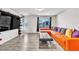 The living room has an orange couch and dark ottoman, plus outside views from windows with black curtains at 5976 Rockway Glen Ave, Las Vegas, NV 89141
