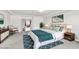 A staged main bedroom with a bed, an accent chair, a night stand, and view into the living room at 5976 Rockway Glen Ave, Las Vegas, NV 89141
