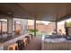 A covered outdoor patio is furnished with barstool seating and is open to an artificial lawn and inground hot tub at 5976 Rockway Glen Ave, Las Vegas, NV 89141