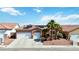 Charming single-story home with a two-car garage, desert landscaping, and solar panels on the roof at 7404 Dry Corral Ln, Las Vegas, NV 89113