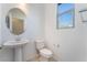 Clean powder room with a pedestal sink, toilet, and a window, offering a simple and functional space at 756 Sleeping City Ave, Henderson, NV 89015