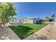 Spacious backyard with green turf, a modern art wall, and mature trees at 7575 Coley Ave, Las Vegas, NV 89117