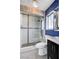 Bathroom featuring a tiled shower with glass door, blue accent wall, and modern vanity at 7575 Coley Ave, Las Vegas, NV 89117