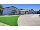 Long driveway and landscaping leading to a house with modern exterior and unique garage door at 7575 Coley Ave, Las Vegas, NV 89117