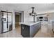 A renovated kitchen with large stainless refrigerator, white cabinets, gray island, and modern light fixture at 7575 Coley Ave, Las Vegas, NV 89117