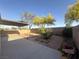 Wide angle view of backyard featuring patio, desert landscaping, mature trees, and block wall at 7611 Avila Beach Ave, Las Vegas, NV 89113