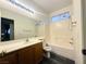 Bright bathroom features a tub with shower and a vanity with solid surface countertop and wood cabinets at 7611 Avila Beach Ave, Las Vegas, NV 89113