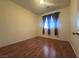 Simple bedroom with hardwood floors, neutral walls, and a window dressed with dark curtains at 7611 Avila Beach Ave, Las Vegas, NV 89113