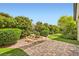 Lush backyard oasis featuring a tranquil water feature, verdant landscaping, and a charming brick patio at 8732 Kendall Brook Cir, Las Vegas, NV 89149