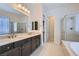 Elegant bathroom featuring double sinks, a large mirror, a walk-in shower, and a soaking tub at 8732 Kendall Brook Cir, Las Vegas, NV 89149