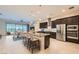 Open-concept kitchen featuring dark wood cabinets, stainless steel appliances, and a breakfast bar seating area at 8732 Kendall Brook Cir, Las Vegas, NV 89149