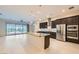 Bright kitchen featuring an island with granite countertop and dark brown cabinets, stainless steel appliances, and tile flooring at 8732 Kendall Brook Cir, Las Vegas, NV 89149