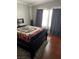 Bedroom featuring a large bed, curtains, and neutral gray walls with hardwood flooring at 8811 Tomnitz Ave # 101, Las Vegas, NV 89178