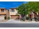 Two-story home featuring a brown two-car garage, tan stucco, stone accents, and front yard trees at 8988 Winchester Ridge St, Las Vegas, NV 89139