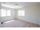 An empty light and bright bedroom with wood floors and two windows at 901 Sir Winston St, Henderson, NV 89052