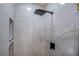 Close-up of a stylish shower with marbled tile, a shower niche, and modern black fixtures at 901 Sir Winston St, Henderson, NV 89052