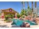 Beautiful pool with rock waterfall, lush tropical landscaping, and a covered outdoor seating area at 912 Santa Ynez Ave, Henderson, NV 89002