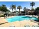 Community pool with clear blue water, palm trees, and lounge chairs at 10001 Peace Way # 2228, Las Vegas, NV 89147