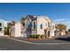 View of the exterior of the apartment complex with tan stucco, red trim, and a row of garages at 10001 Peace Way # 2228, Las Vegas, NV 89147