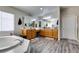 Bathroom with dual vanities, mirrors, wood-look flooring, and a soaking tub at 1048 Painted Daisy Ave, Henderson, NV 89074