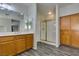 Bathroom with wood cabinets, shower with glass door, and large mirrors above vanity at 1048 Painted Daisy Ave, Henderson, NV 89074