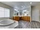 Bright main bathroom with a soaking tub, wooden vanity, and large mirrors at 1048 Painted Daisy Ave, Henderson, NV 89074